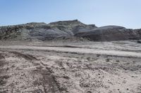 a barren and muddy landscape with rocks, rocks, dirt, dirt and grass on the ground