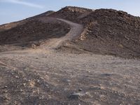 a truck on a dirt road in the desert with rocks and stones on the ground