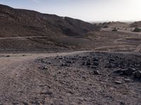 a truck on a dirt road in the desert with rocks and stones on the ground