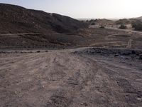 a truck on a dirt road in the desert with rocks and stones on the ground