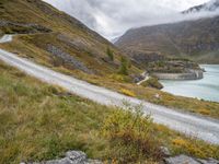 a car that is driving down a dirt road near the water and a mountain road