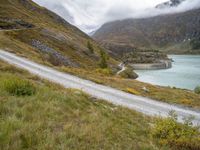 a car that is driving down a dirt road near the water and a mountain road