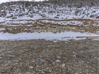 a snow covered slope with rocks and rocks surrounding the edge of it and snow covering on the ground