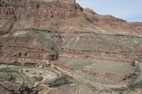 a lone rider rides through the landscape and overlooks a gorge below them in an arid area