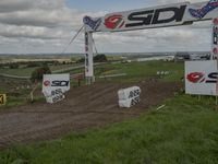 several race signage and dirt bike course on a hill side under clouds on a cloudy day