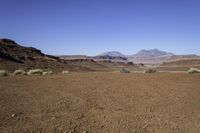 a deserted desert area in the middle of the day with mountains and rocky cliffs in the distance