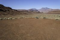 a deserted desert area in the middle of the day with mountains and rocky cliffs in the distance