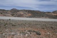 a large arid area with a road and mountains behind it and a blue sky above the ground