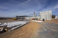 a white metal pole sits on dirt and dirt next to steel poles on a construction site