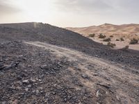 a truck on a dirt road in the desert with rocks and stones on the ground