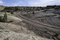 a road with rocks and scruby scrub in the background, and dirt trail in the foreground