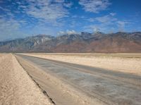 empty desert road with mountain in the distance in a dry area with no grass or shrubs