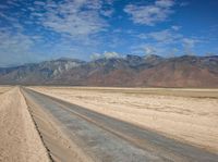 empty desert road with mountain in the distance in a dry area with no grass or shrubs