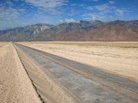 empty desert road with mountain in the distance in a dry area with no grass or shrubs