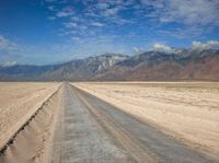 empty desert road with mountain in the distance in a dry area with no grass or shrubs