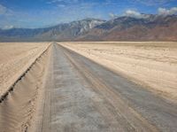 empty desert road with mountain in the distance in a dry area with no grass or shrubs