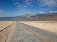 empty desert road with mountain in the distance in a dry area with no grass or shrubs