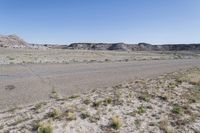 a dry landscape with mountains and bushes on either side of the road in the middle of nowhere