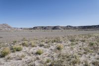 a dry landscape with mountains and bushes on either side of the road in the middle of nowhere