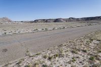 a dry landscape with mountains and bushes on either side of the road in the middle of nowhere