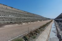 road with rocky hill with sand and water in the distance on it's side