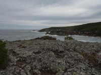 rocks, cliffs and a body of water with a cloudy sky in the background on an overcast day