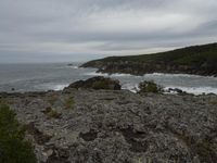 rocks, cliffs and a body of water with a cloudy sky in the background on an overcast day