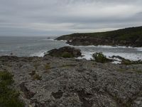 rocks, cliffs and a body of water with a cloudy sky in the background on an overcast day