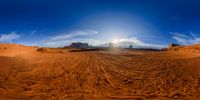 the sun shines brightly through a blue sky over an arid plain covered with dirt and sand