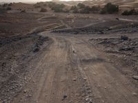 a truck on a dirt road in the desert with rocks and stones on the ground