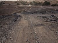 a truck on a dirt road in the desert with rocks and stones on the ground