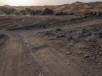 a truck on a dirt road in the desert with rocks and stones on the ground