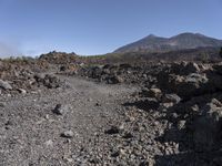 there is a dirt road leading through the mountains and lava rocks and boulders to the right