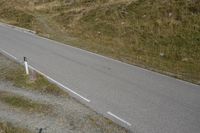 a motorcycle parked on a small mountain side road near mountains with no cars driving on it