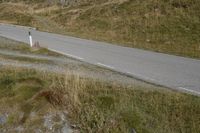 a motorcycle parked on a small mountain side road near mountains with no cars driving on it