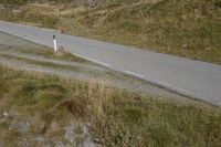 a motorcycle parked on a small mountain side road near mountains with no cars driving on it