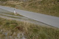 a motorcycle parked on a small mountain side road near mountains with no cars driving on it