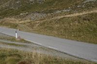 a motorcycle parked on a small mountain side road near mountains with no cars driving on it