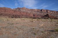 a horse grazes in the open land between two cliffs of a desert area,