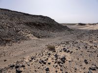 a truck on a dirt road in the desert with rocks and stones on the ground