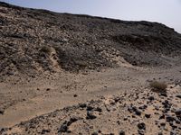 a truck on a dirt road in the desert with rocks and stones on the ground