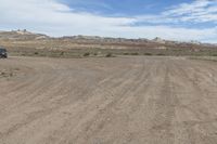 an empty field next to a big mountain with rocks in the background of the picture