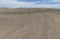 an empty field next to a big mountain with rocks in the background of the picture