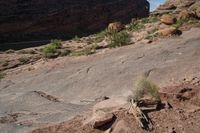 a man hiking up a big rocky cliff, on the trail down to the falls