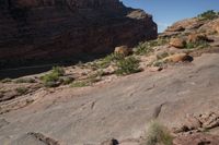 a man hiking up a big rocky cliff, on the trail down to the falls