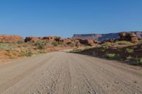 dirt road with mountains and vegetation and a blue sky in the background with a clear sky