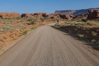 dirt road with mountains and vegetation and a blue sky in the background with a clear sky