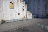 a concrete street next to an old building with a broken window and broken doors,