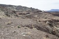 some dirt and rocks on a hill in the desert, and mountains in the background