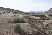 some dirt and rocks on a hill in the desert, and mountains in the background